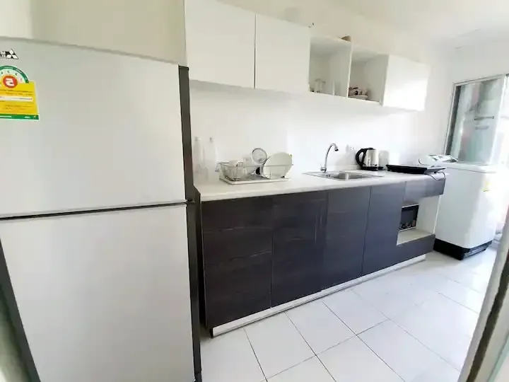 Modern kitchen counter with full-size refrigerator and kitchenware